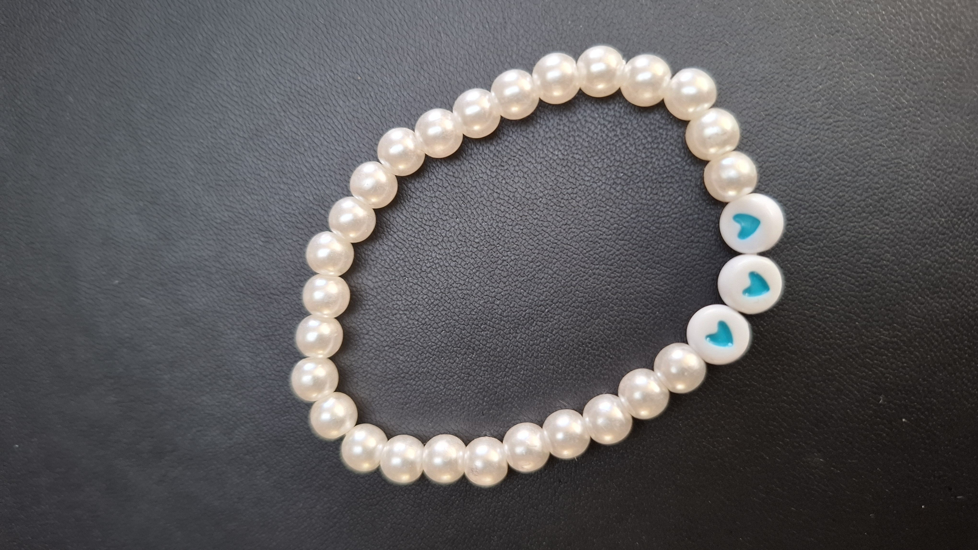 armband met witte kralen en 3 blauwe hartjes
