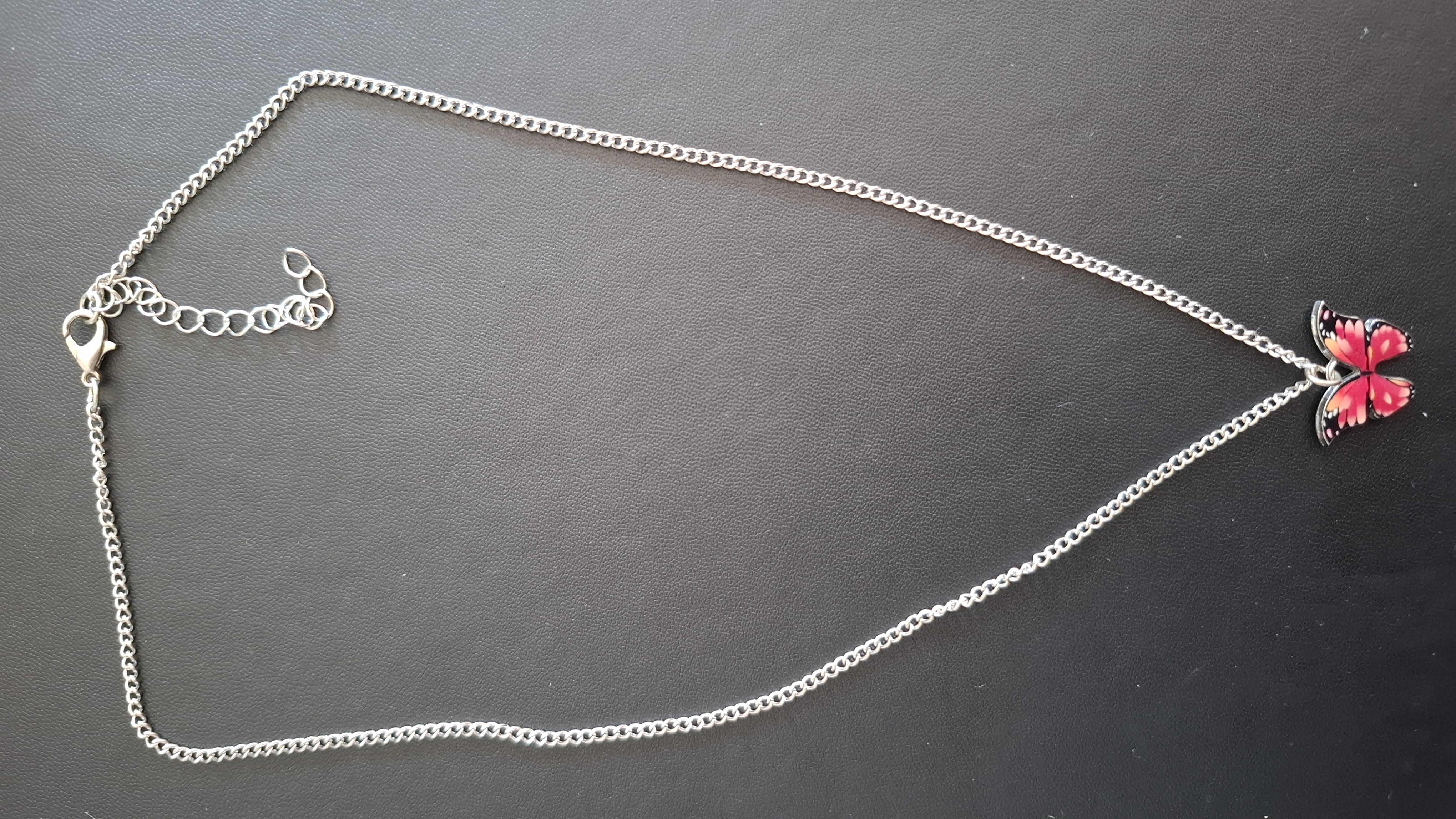 ketting in zilveren kleur met rood/roze vlinder