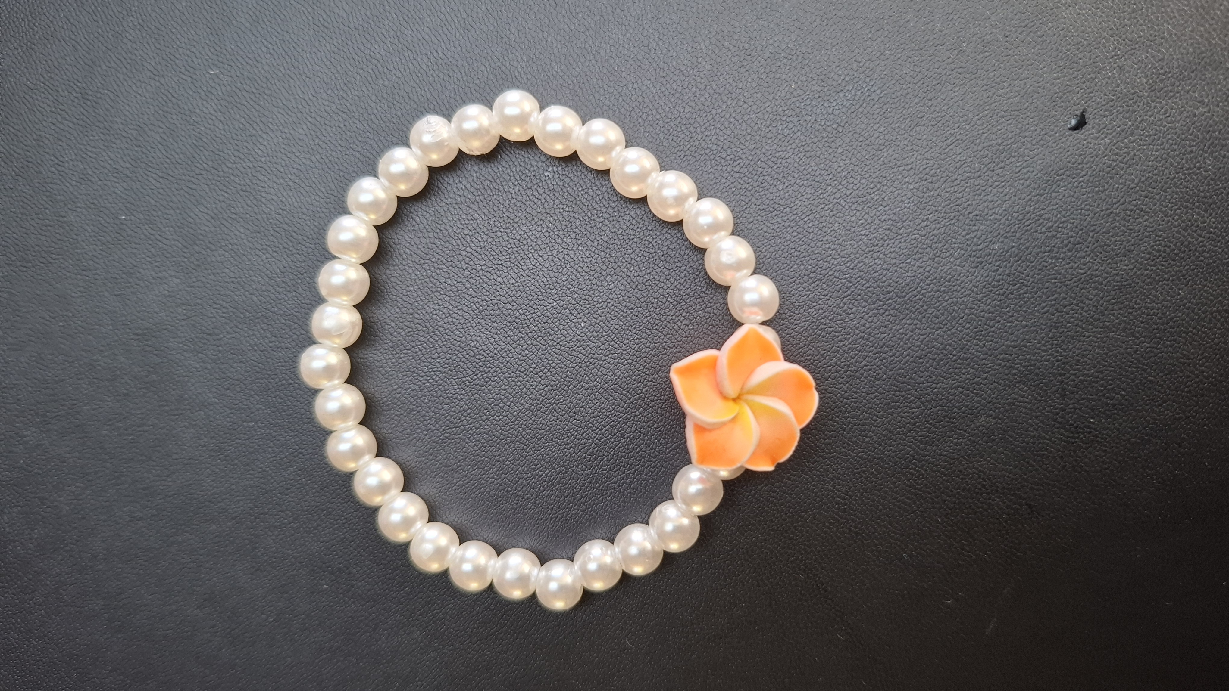 armband witte kralen met oranje bloem