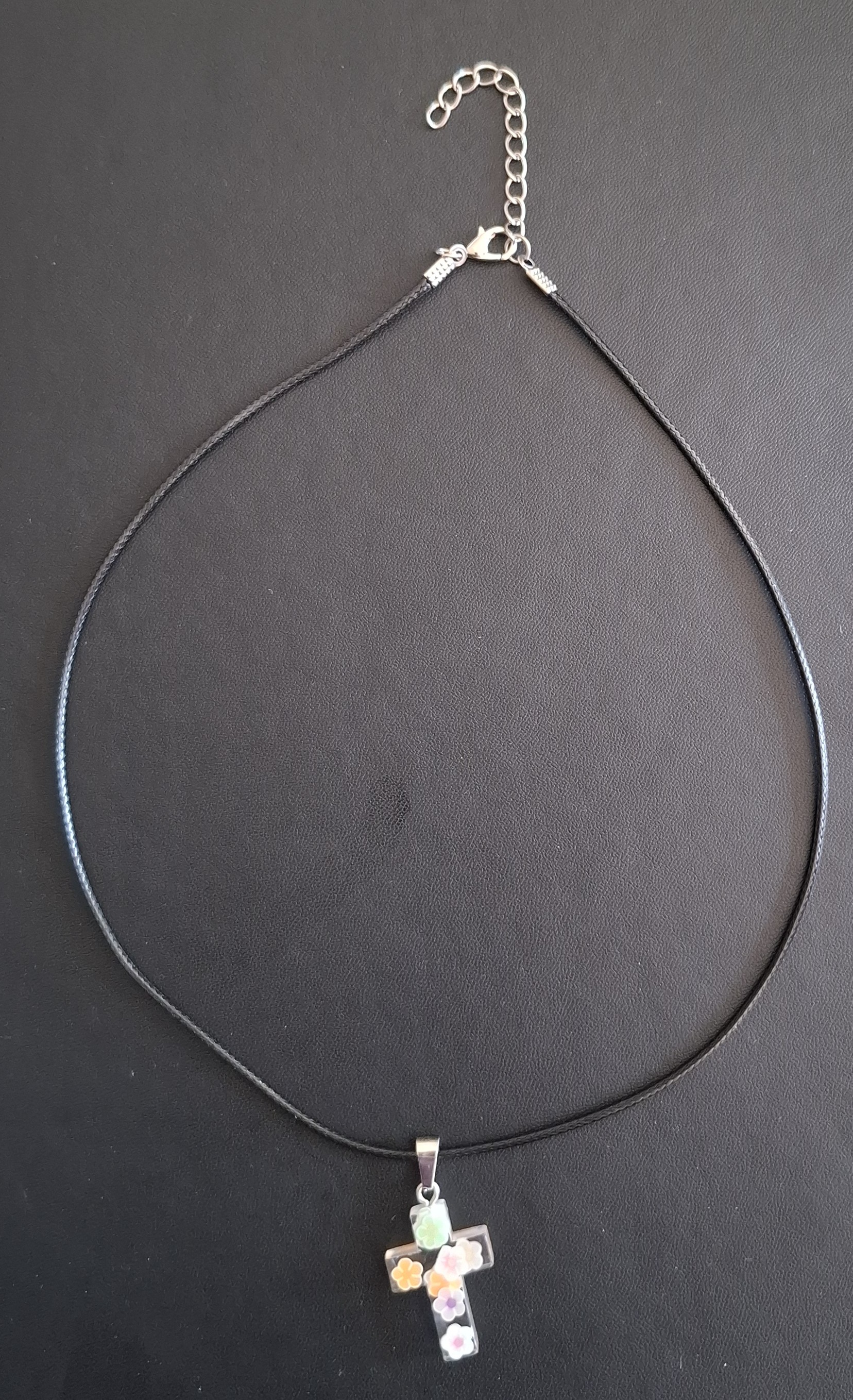 zwarte kunststof ketting met doorzichtig kruis met oranje/paars/groen bloemetjes 