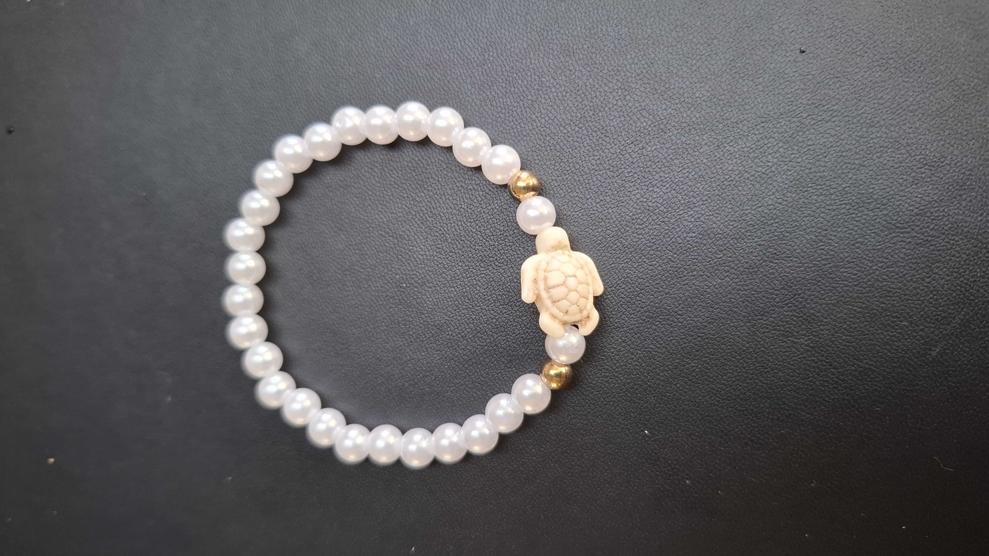 armband met witte en goud kleurige kralen en witte schilpad