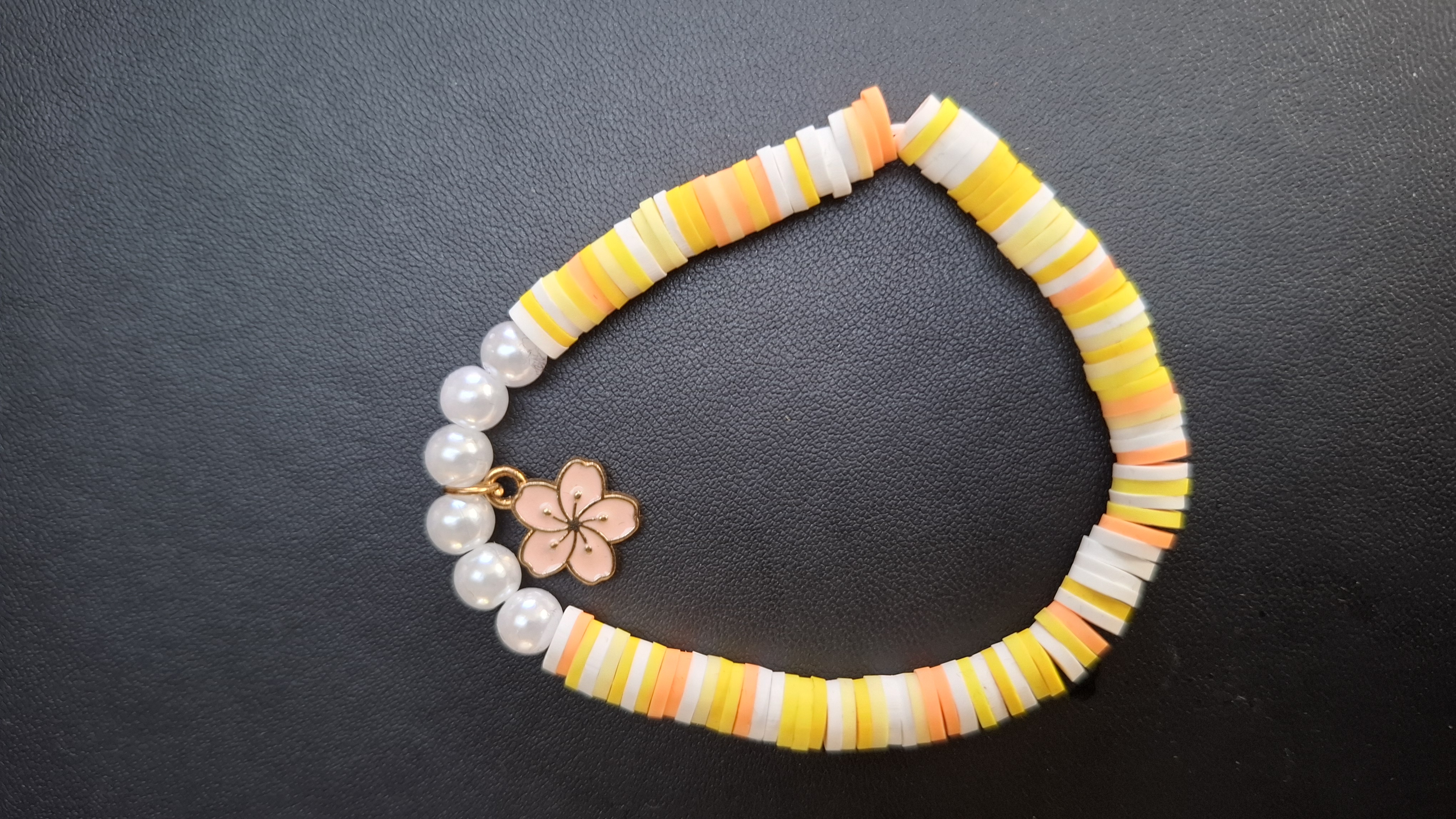 armband geel/wit/oranje met 6 kralen en roze bloem