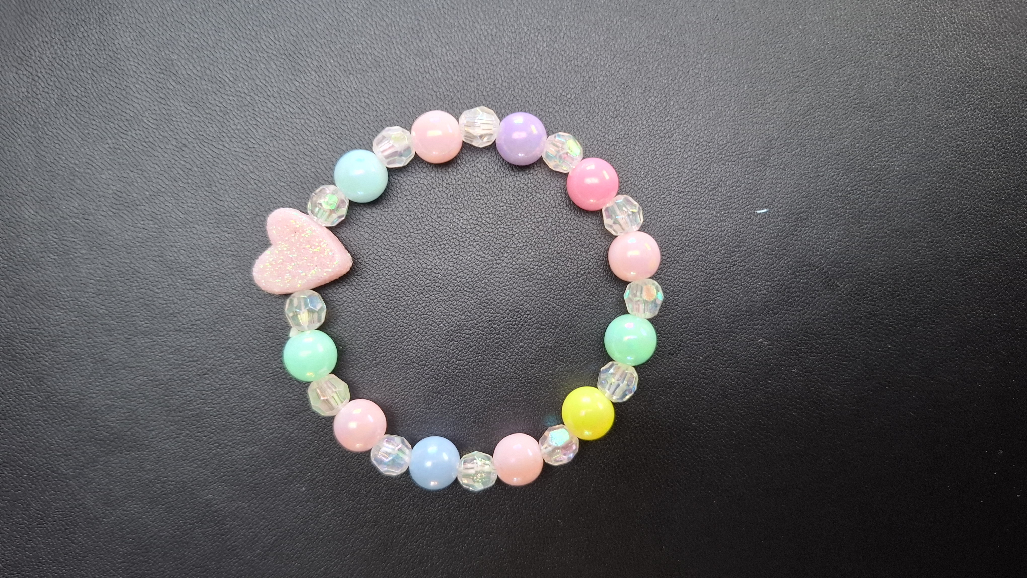 armband met doorzichtige en gekleurde kralen en roze hartje