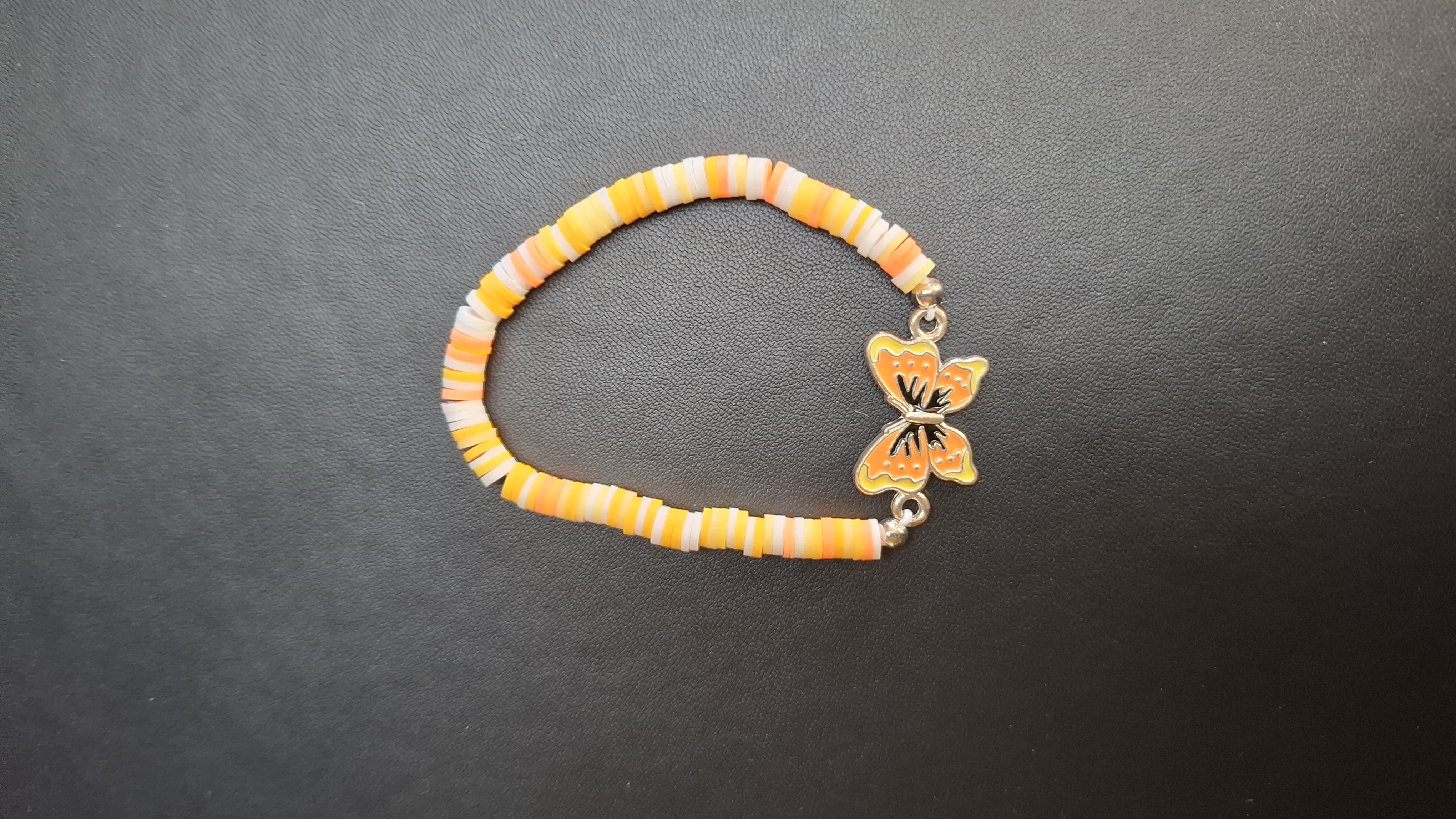 armband oranje/geel/wit met oranje/gele vlinder