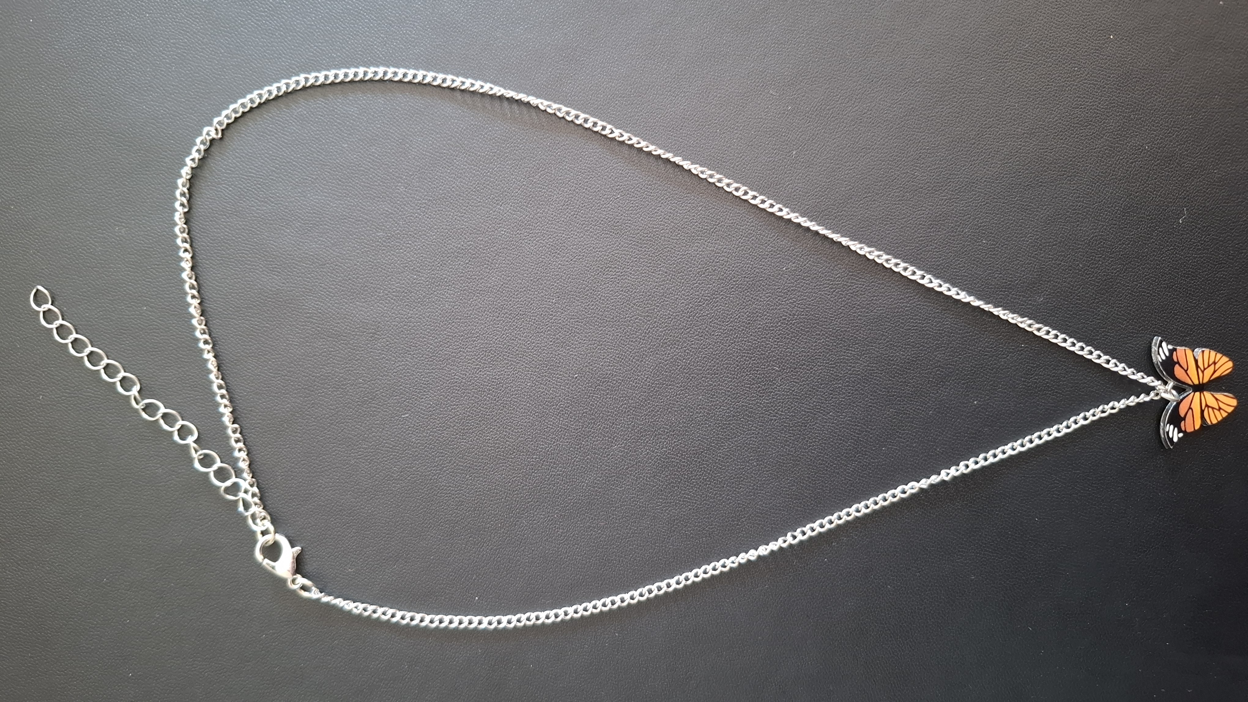 ketting in zilveren kleur met oranje/zwarte vlinder
