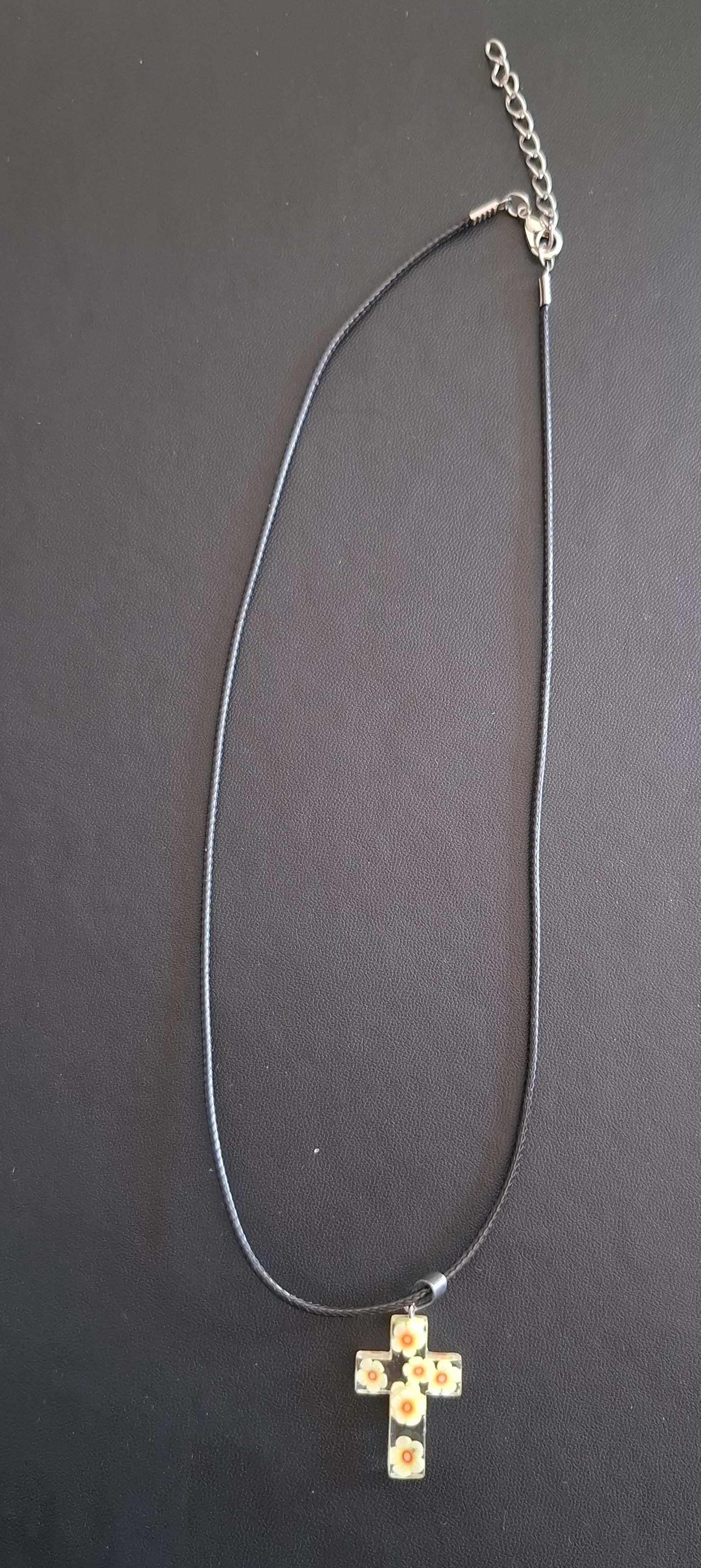 zwarte kunststof ketting met doorzichtig kruis met wit/gele bloemetjes