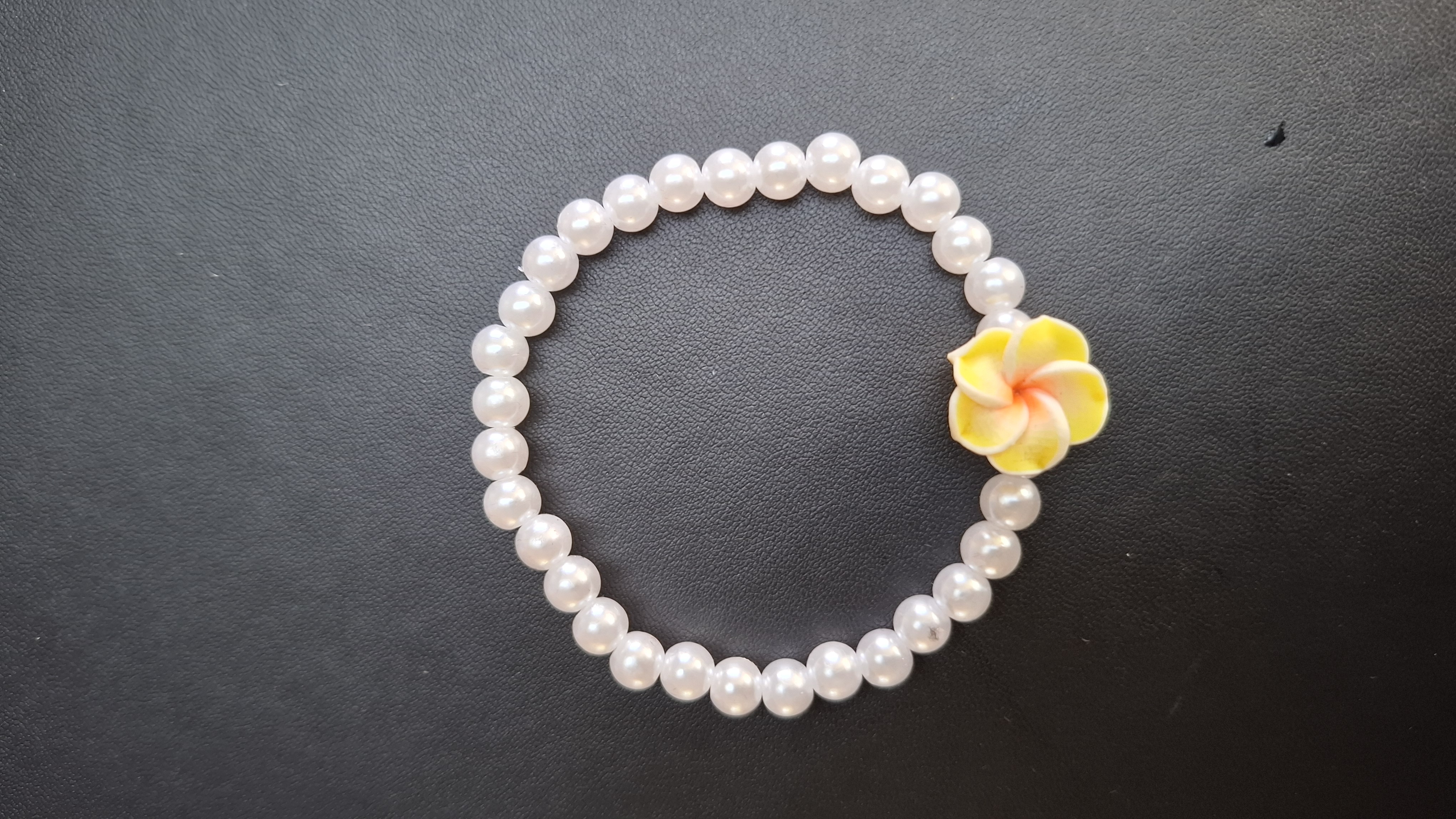 armband witte kralen met gele bloem