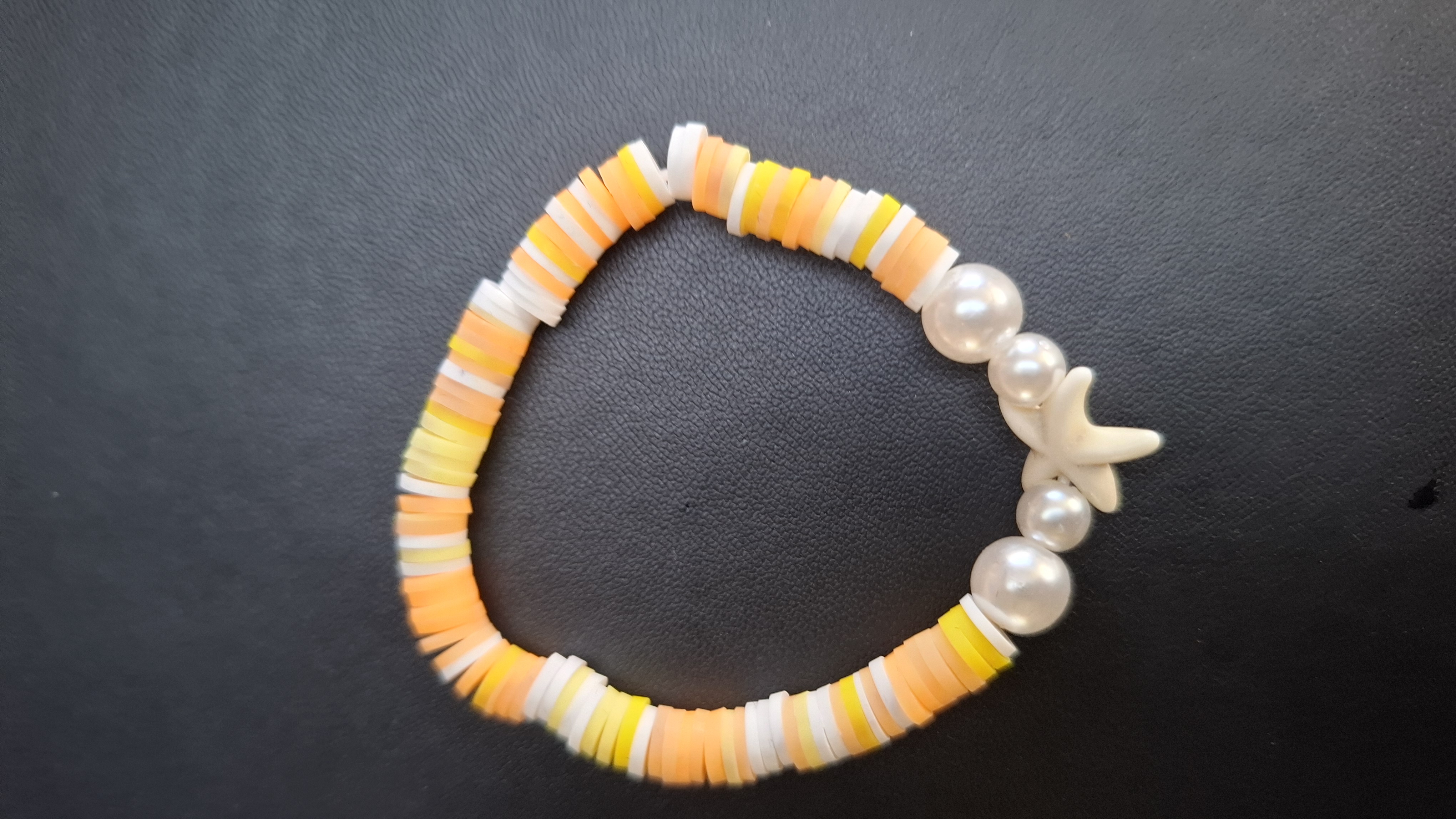 armband geel/oranje/wit met 4 witte kralen en zeester